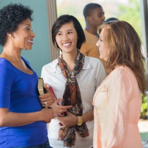 Women in discussion holding Religious texts Diverse girl friends talking in lobby of church after service