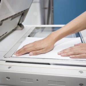hands putting a sheet of paper into a copying device woman hands putting a sheet of paper into a copying device