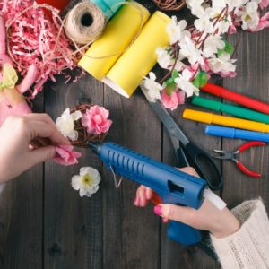 Woman glue handmade flowers with melt gun Woman glue handmade flowers with melt gun. Top view