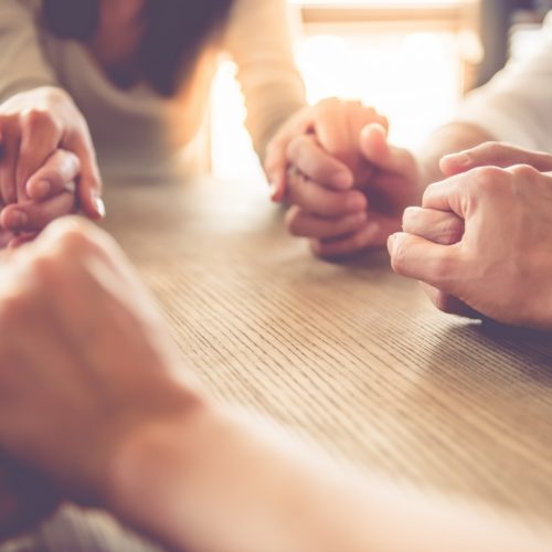 Business people working Cropped image of beautiful business team holding hands and praying while sitting in office
